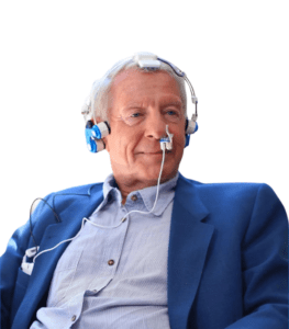 Older man in blue jacket wearing transcranial headset and intranasal devices