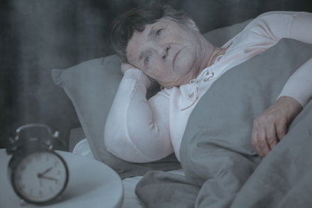 Elderly woman lying in bed with eyes open