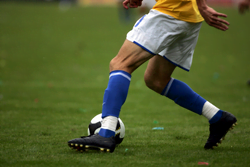 Soccer player with blue socks kicking soccer ball