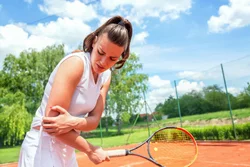 Women tennis player holding sore elbow